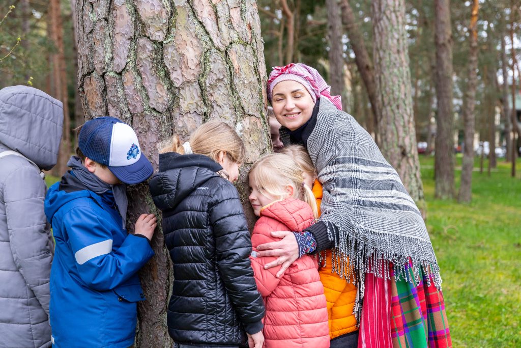 Palangos Jurginės. Vaikai mokosi išgirsti gamtą. Pridėję ausis prie medžio - klausosi.