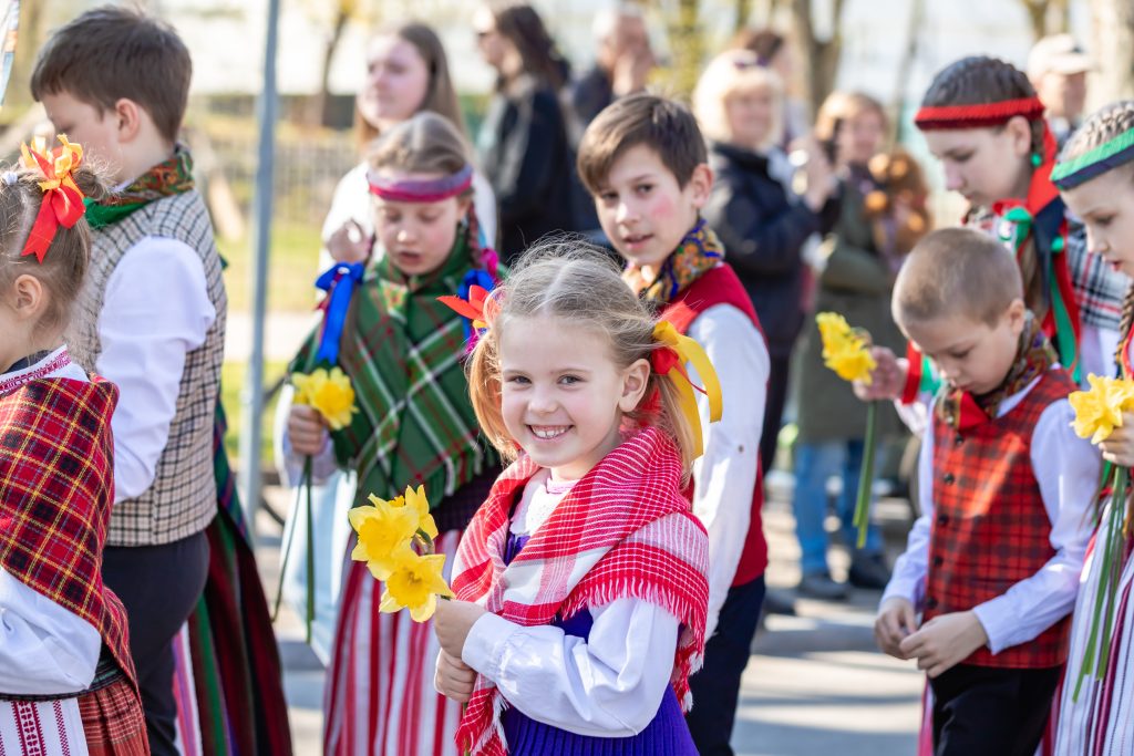 Palangos Jurginės. Vaikai apsirengę tautiškai nešasi gėlių puokštės